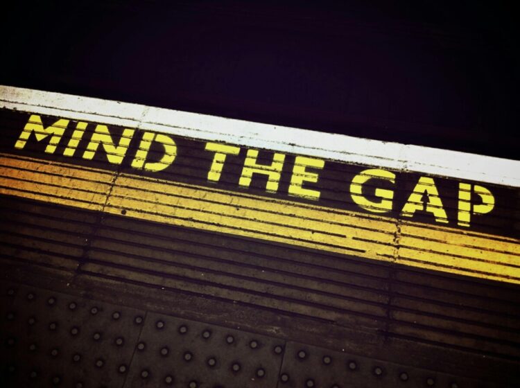 A picture of the edge of the train platform in the London Subway where it says Mind the Gap