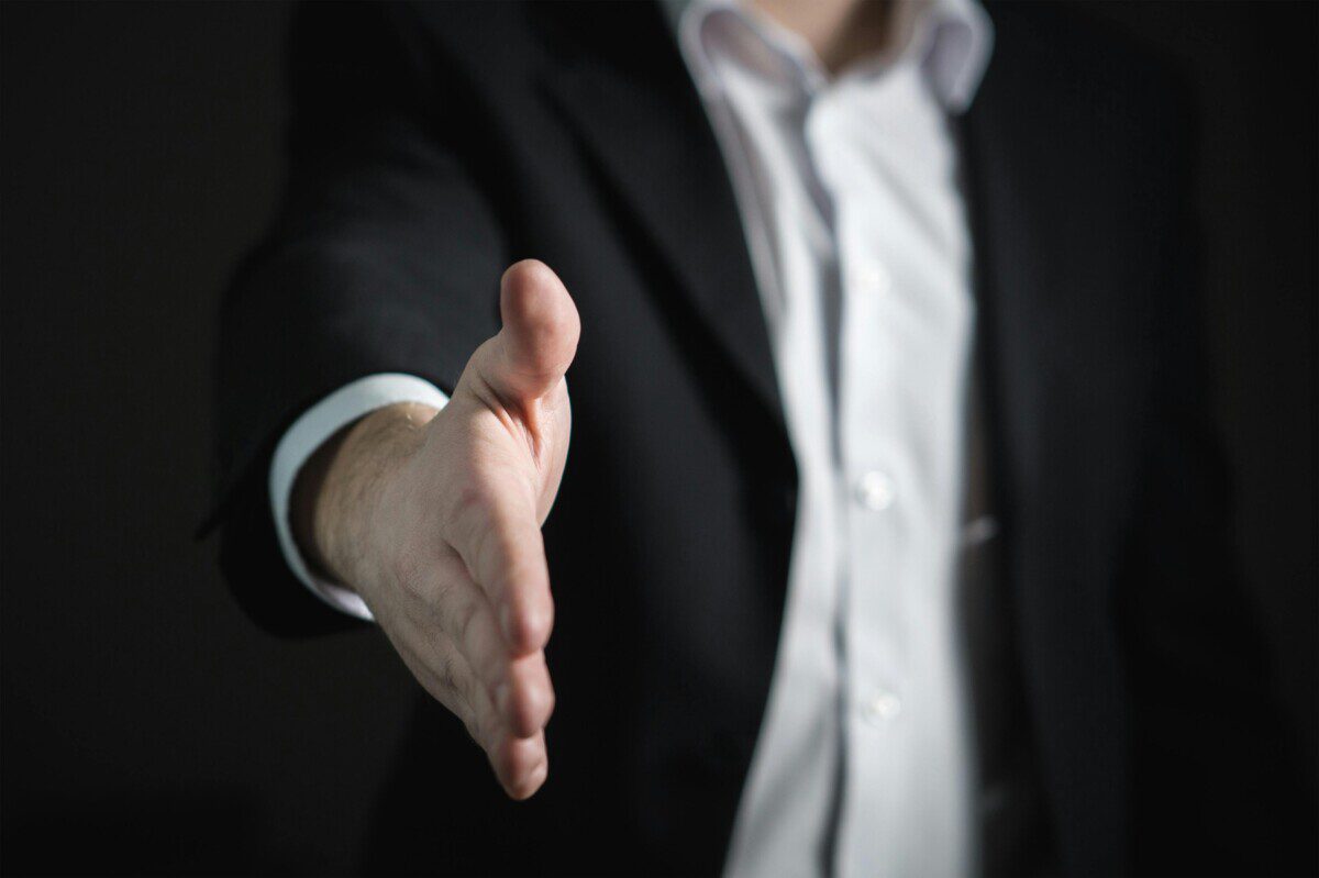 A man's hand reaching toward you to shake your hand.